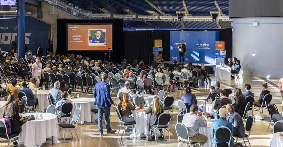 Man speaks to crowd while on stage during PitchMI competition