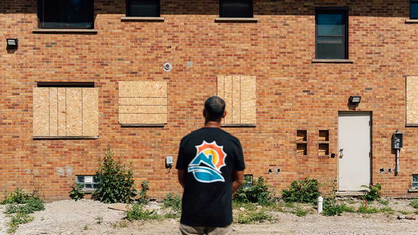 Shaker manns stands outside of a apartment complex under construction with his back to the camera